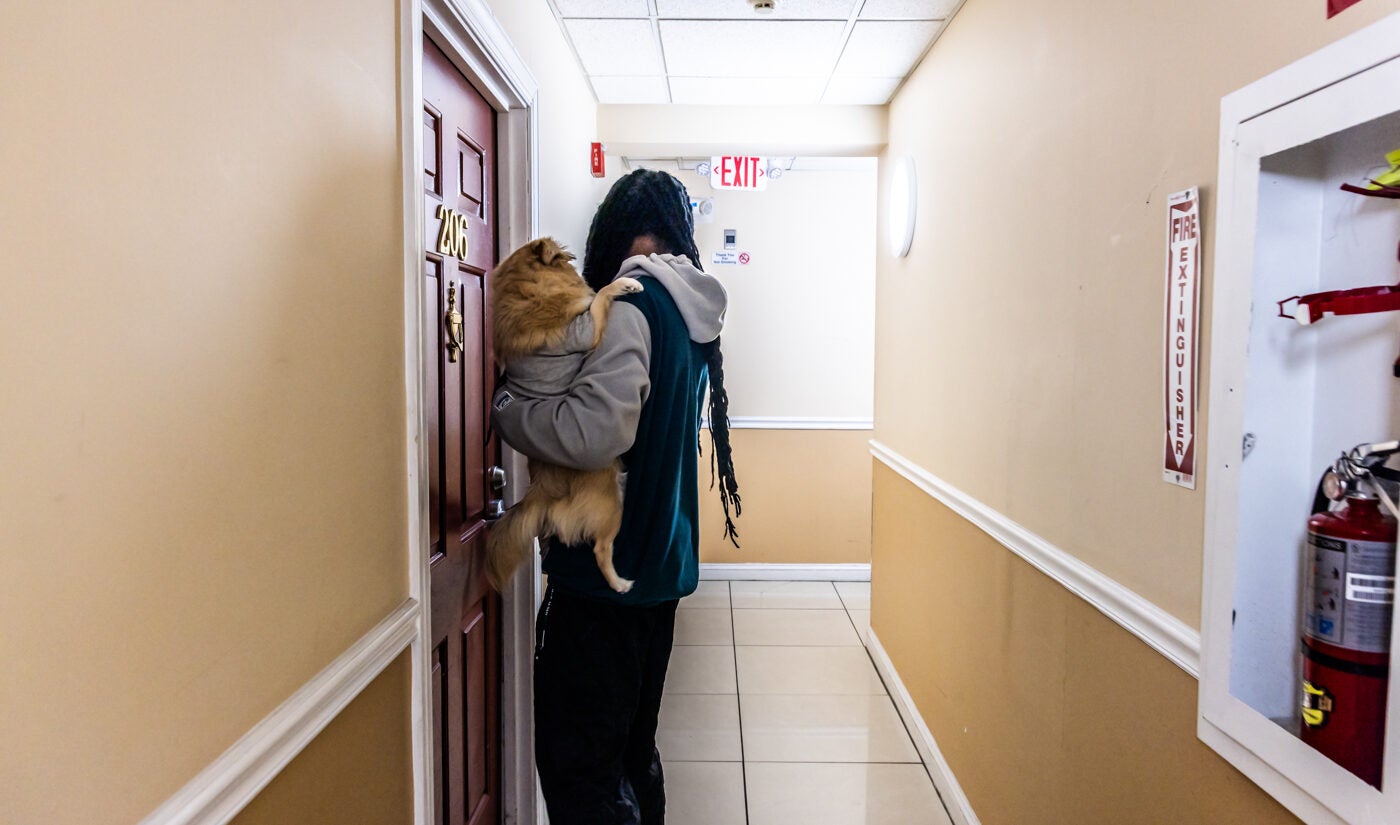 A man carrying his dog in an apartment building hallway