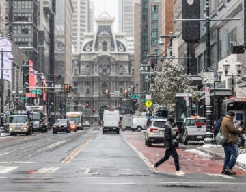 two people cross the street near City Hall