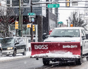 A city plow truck driving a snowy street