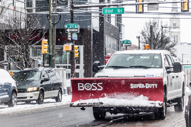 A city plow truck driving a snowy street