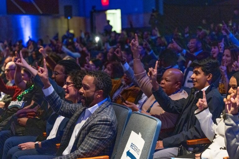 people in the crowd each raise a finger