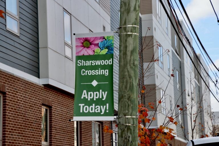 a sign on a pole reads Sharswood Crossing Apply Today!