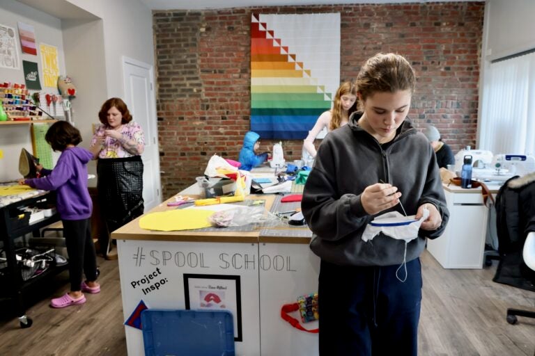 Annabelle Vincent embroiders with other kids working on projects