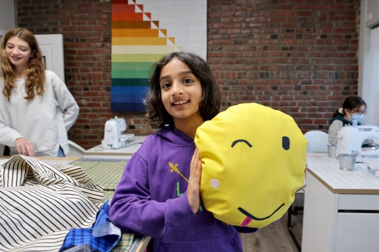 Asha Vedanthan holds a pillow and smiles