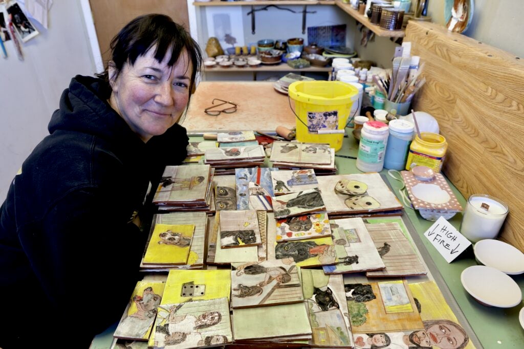 Anne Koszalka with a table full of her artwork