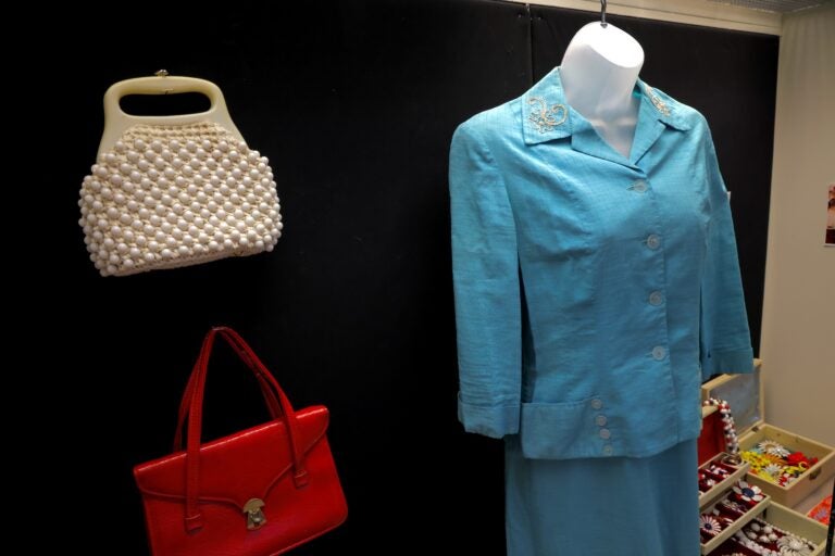 A blue blouse, jewelry and purses hang in a display