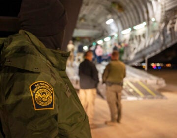 A U.S. Customs and Border Protection agent watches as undocumented immigrants are loaded onto a plane