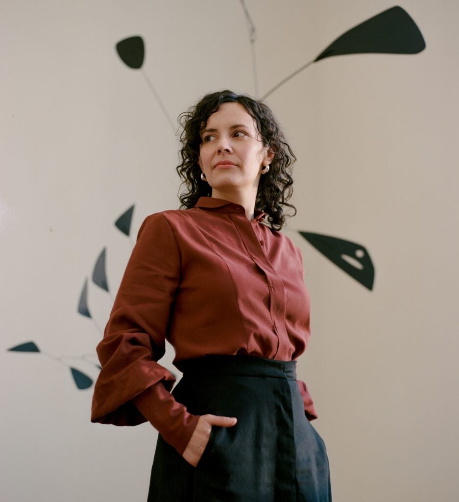 Juana Berrío smiles in front of a sculpture