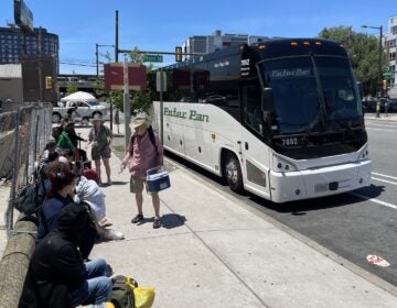 People handing out water bottles to a group of people waiting to get onto a bus