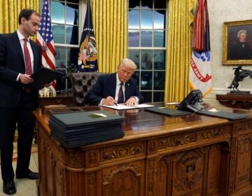 Trump signing an oder at his desk in the oval office