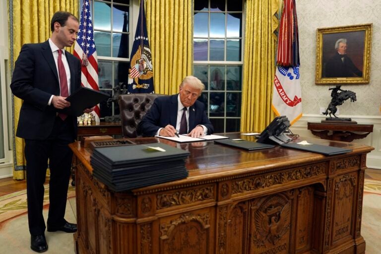 Trump signing an oder at his desk in the oval office