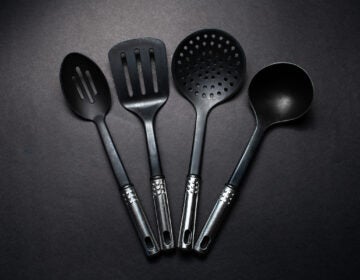 Studio picture of black plastic kitchen utensils with chromed handles. (Bigstock/Lalandrew)