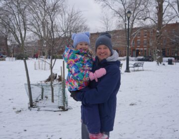 A father and daughter playing in the snow at the park