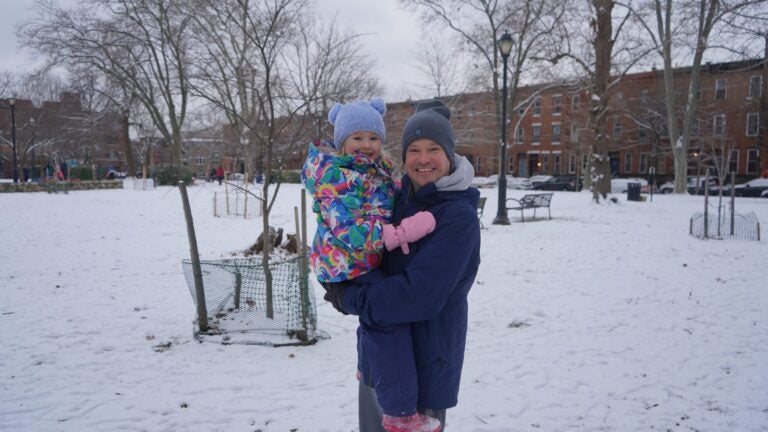 A father and daughter playing in the snow at the park