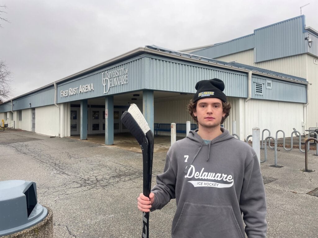 An ice hockey player at the University of Delaware stands outside an ice rink