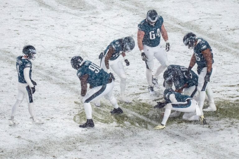 Eagles players move snow so Jake Elliot can kick a field goal