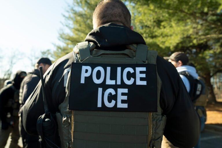 an ICE agent wears a vest reading POLICE ICE