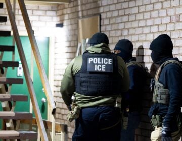 Three ICE agents outside a building