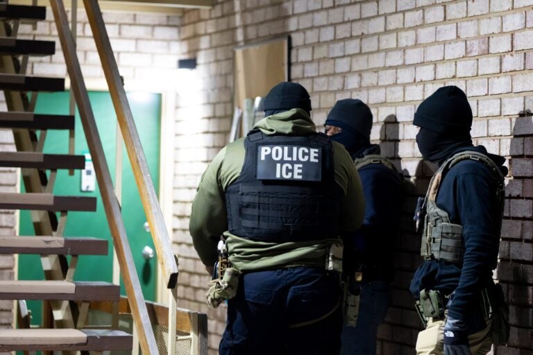 Three ICE agents outside a building