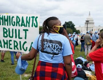 a person holds a sign reading IMMIGRANTS BUILT AMERICA