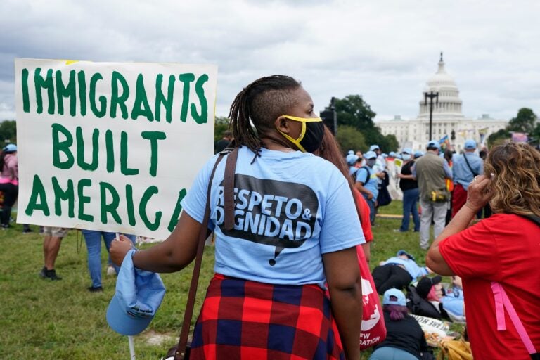 a person holds a sign reading IMMIGRANTS BUILT AMERICA