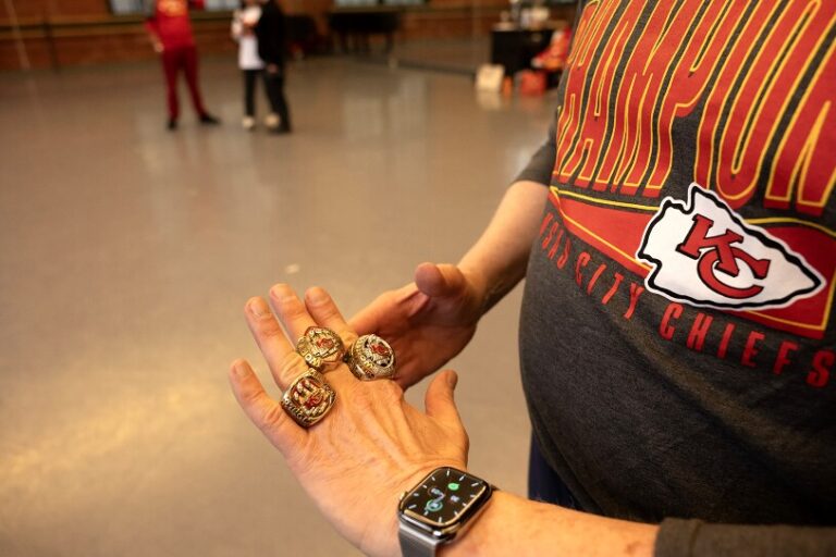 A man shows off three Super Bowl rings on his hand