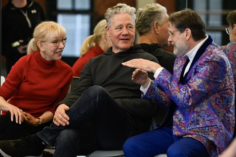 A woman, her husband and a man in a colorful suit talk while sitting down