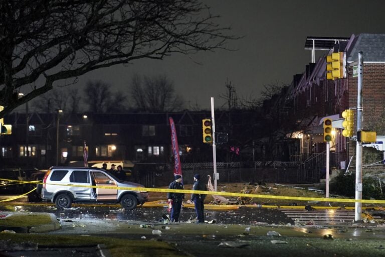 Police and firefighters respond at the scene after a small jet crashed into homes in Northeast Philadelphia