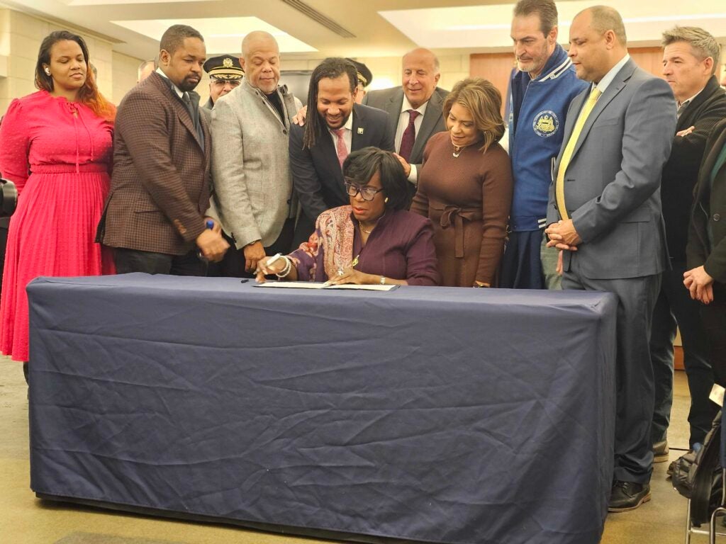 Mayor Parker signs an executive order as others watch on