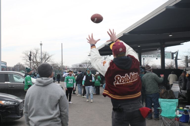 A Commanders fan throws a football with Eagles fans