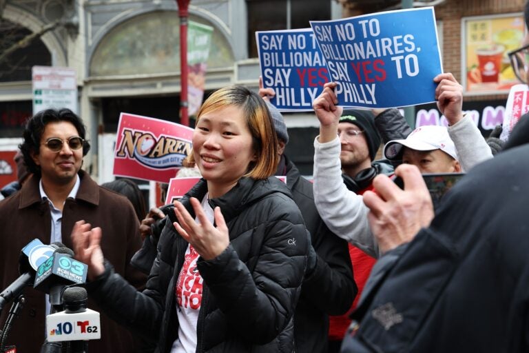 Vivian Chang stands in front of signs reading SAY NO TO BILLIONAIRES, SAY YES TO PHILLY