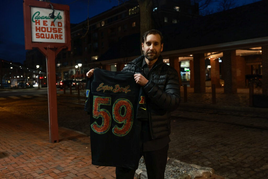 Peter Pantina holds a jersey and smiles