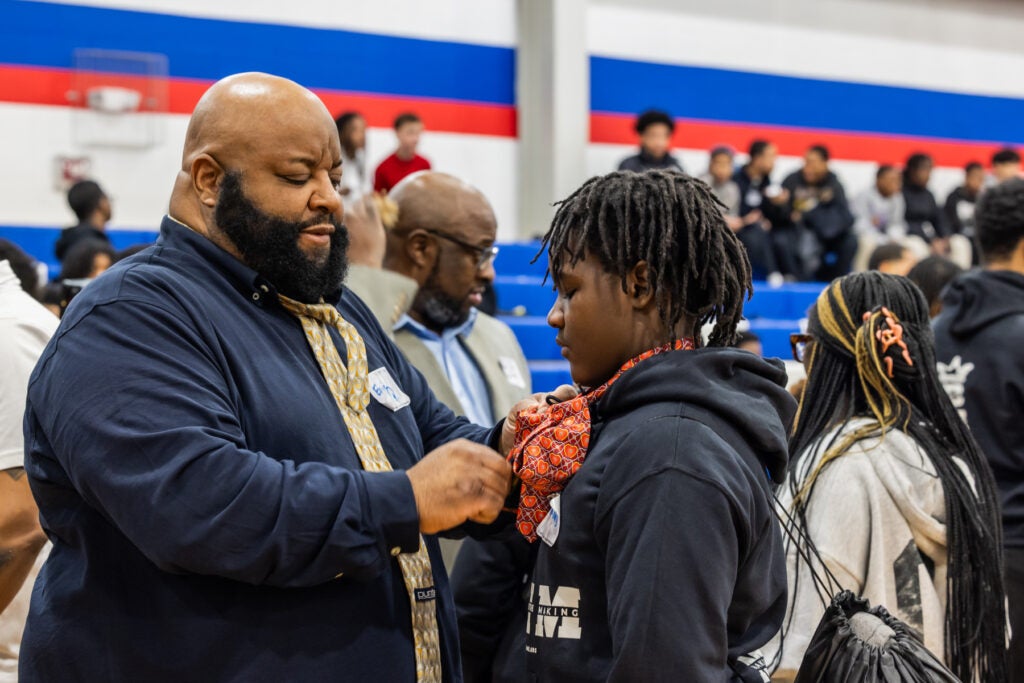 A teen gets help tying his tie