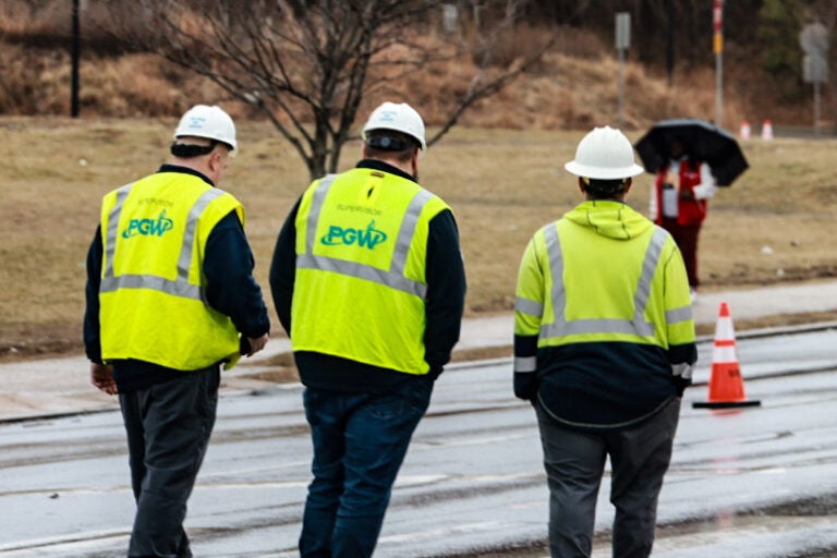 Three people in the street wearing bright yellow PGW vests