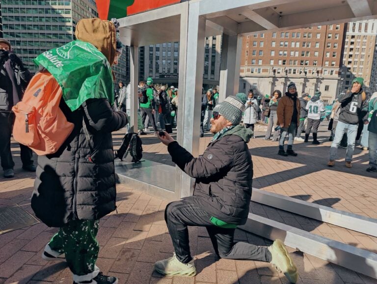 Nicholas Maestrale got down on one knee to pop the question to Olivia Dees during the Eagles victory parade. (Peter Crimmins/WHYY)
