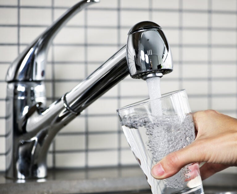 Filling glass of water from stainless steel kitchen faucet. (Bigstock/elanathewise)