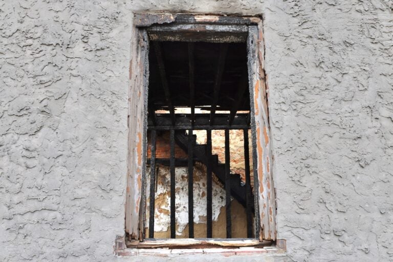 Charred beams and stairs seen through a window