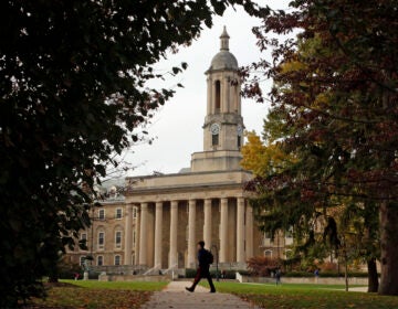 FILE- In this Nov. 9, 2017, file photo people walk by Old Main on the Penn State University main campus in State College, Pa.  (AP Photo/Gene J. Puskar, File)