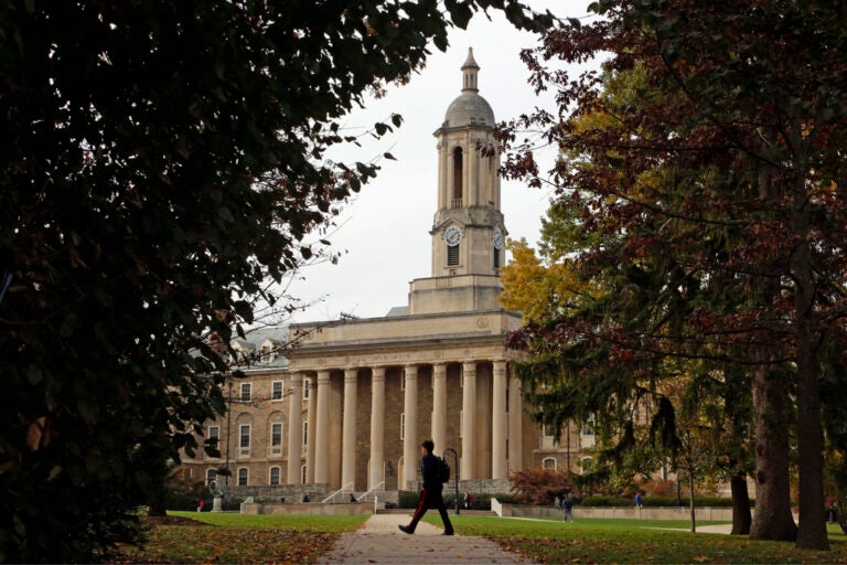 FILE- In this Nov. 9, 2017, file photo people walk by Old Main on the Penn State University main campus in State College, Pa.  (AP Photo/Gene J. Puskar, File)