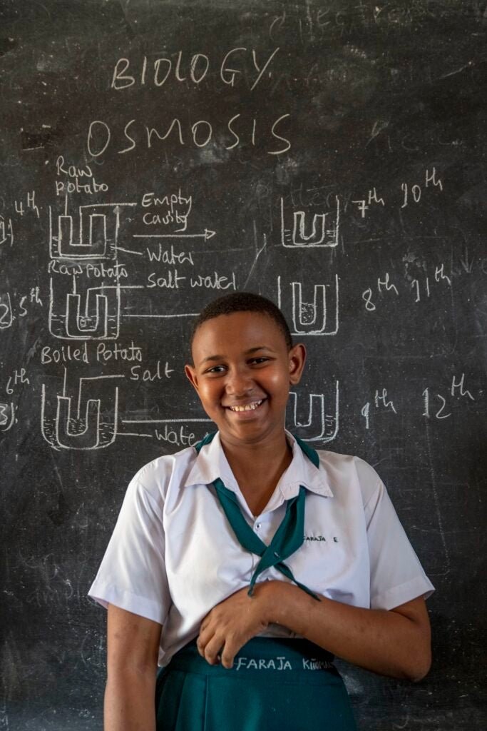 A student poses for a photo in front of a chalkboard