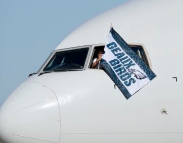 A pilot waves a flag out of the cockpit window that says 'Geaux Birds'