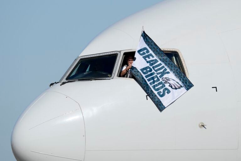 A pilot waves a flag out of the cockpit window that says 'Geaux Birds'