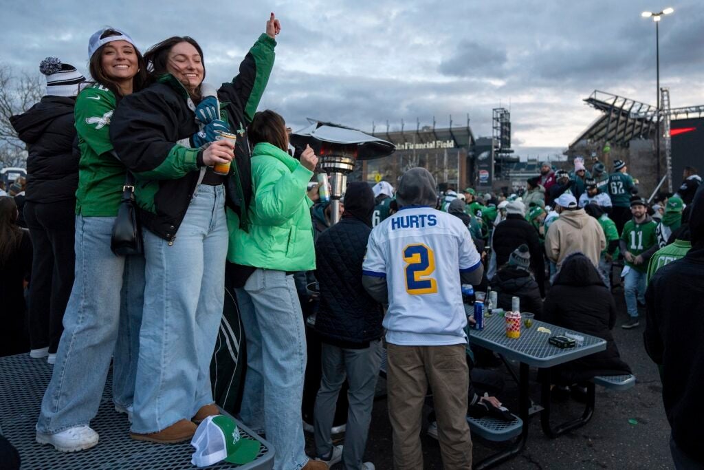 Eagles fans standing on a table cheering at the watch party