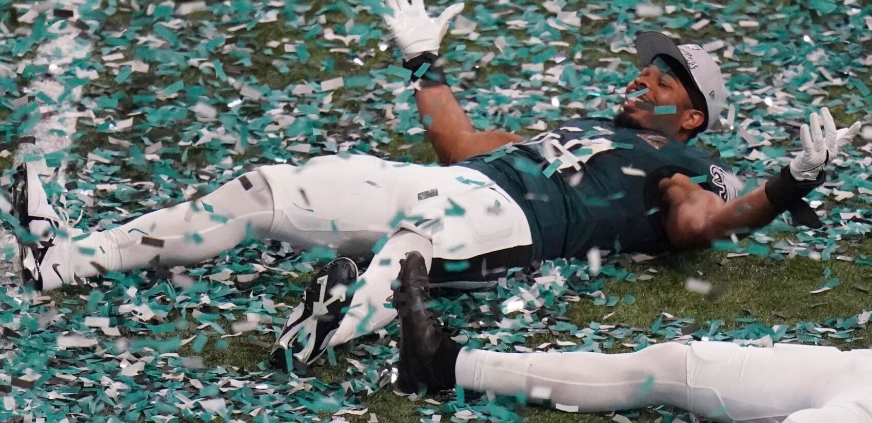 Jeremiah Trotter Jr. making snow angels in the confetti on the field