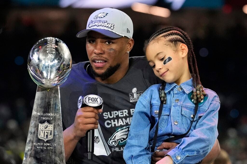 Saquon Barkley answering questions with his daughter sitting in his lap