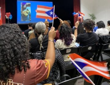 people hold Puetro Rican flags at an event