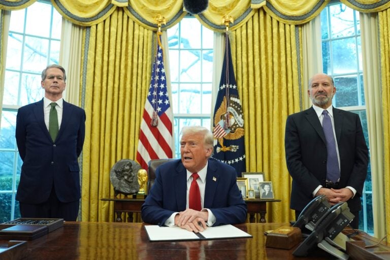 Donald Trump sitting while Scott Bessent and Howard Lutnick stand