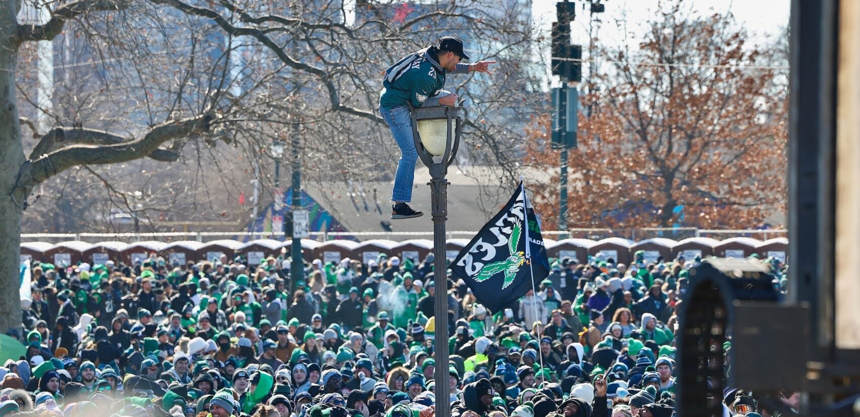 A man is on top of a pole overlooking the crowd