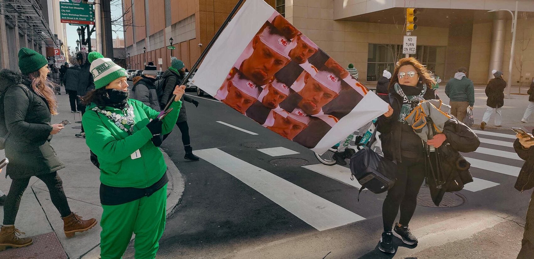 A woman waves a homemade flag with pictures of a sad looking Patrick Mahomes