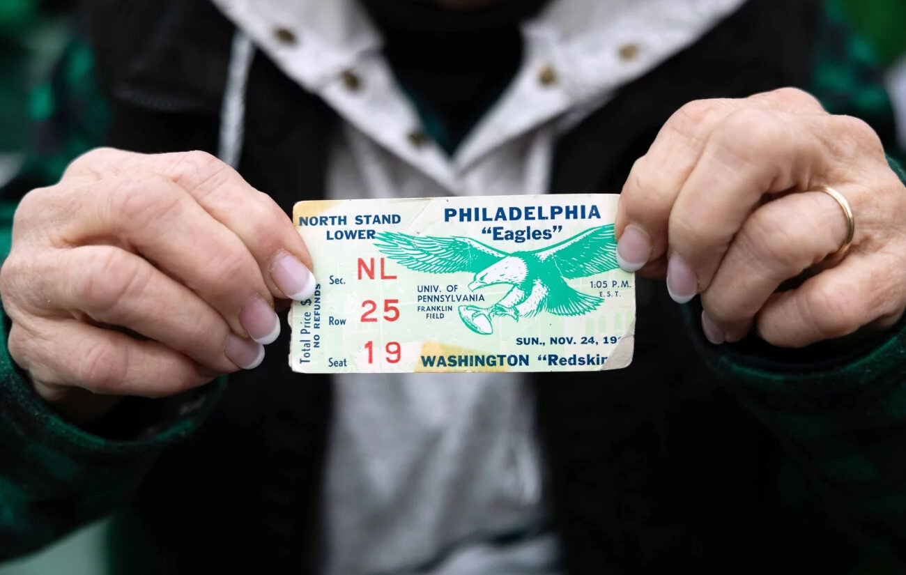 Eileen Zolotorofe holds up a ticket for an Eagles-Commanders NFC championship game